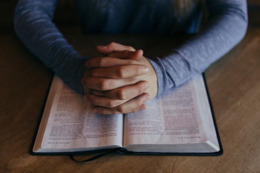 hands folded on bible
